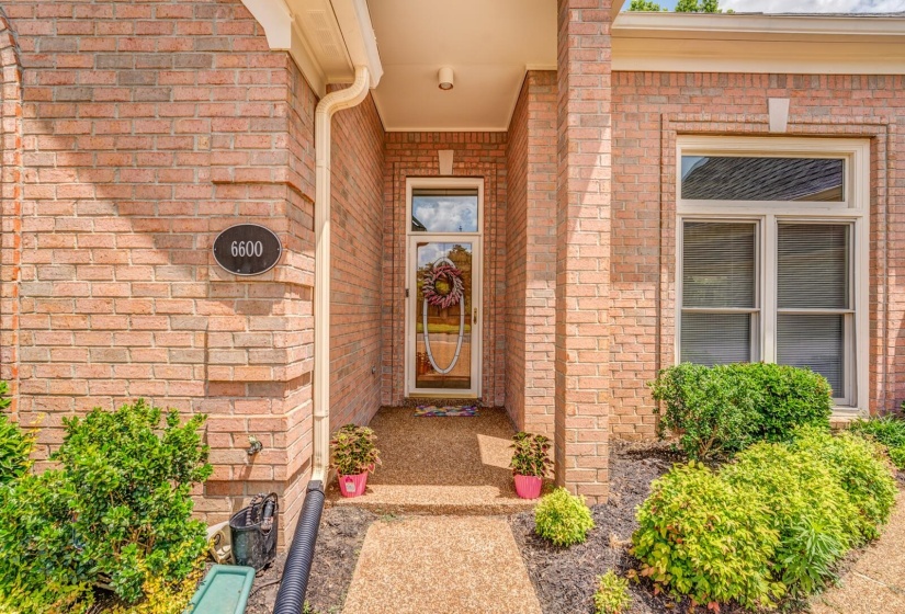 Brick exterior with a covered entry, glass-paneled front door, and a multi-pane window