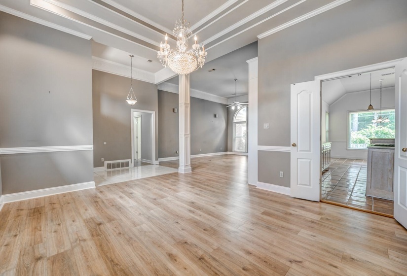Open-concept living space with wood-finish flooring, a coffered ceiling, and a prominent chandelier