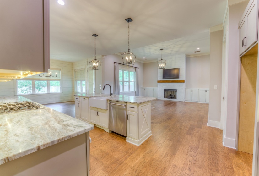 Kitchen island with a farmhouse sink, stainless steel dishwasher, and two pendant light fixtures
