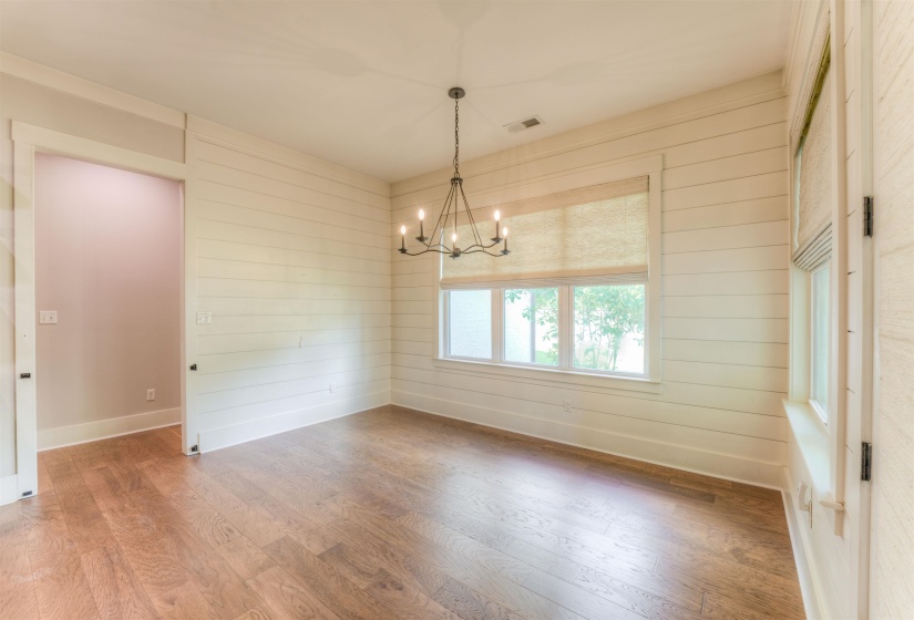 Room featuring wood-finish flooring, shiplap walls, and a multi-pane window with a natural fiber shade