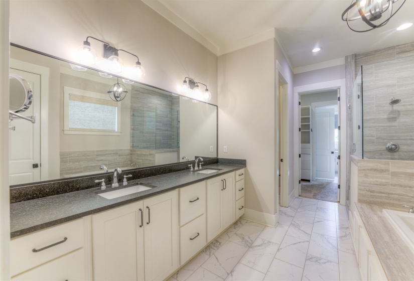 Spacious bathroom featuring a dual vanity with white cabinetry, dark countertops, and undermount sinks