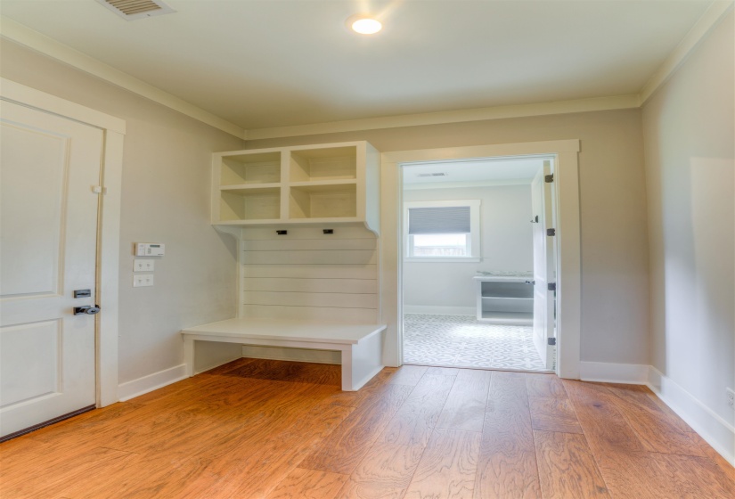 Mudroom entry featuring built-in bench seating, upper shelving, and coat hooks