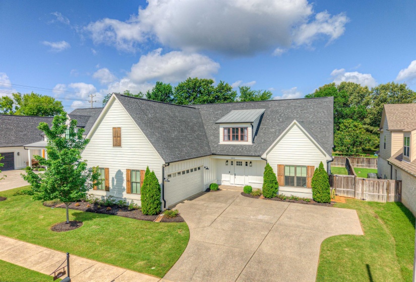 Modern farmhouse exterior featuring white siding, a dark roof, and wood-finish shutters