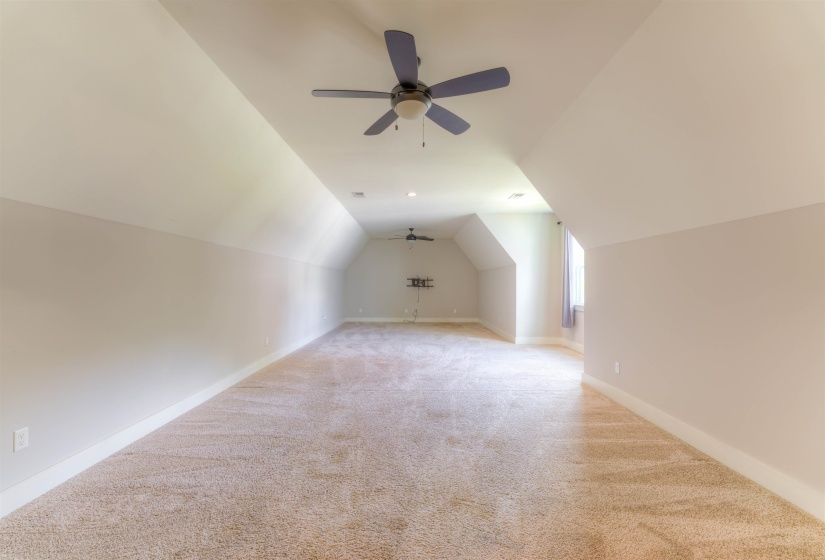 Spacious bonus room featuring vaulted ceilings, plush carpeting, multiple ceiling fans, recessed lighting, and a prominent window