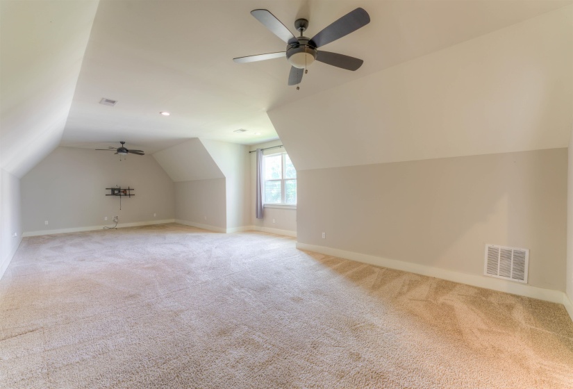 Spacious bonus room featuring vaulted ceilings, plush carpet flooring, recessed lighting, and two ceiling fans