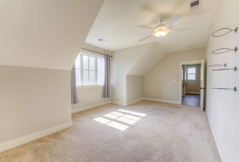 Spacious room featuring vaulted ceilings, neutral-toned carpeting, and a ceiling fan with integrated lighting