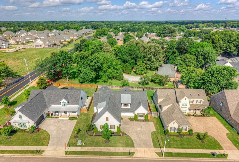 Aerial perspective showcasing a residential street with multiple properties, each featuring a pitched roof, attached garage, concrete driveway, and landscaped front yard