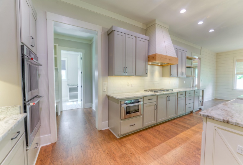 Kitchen featuring light gray cabinetry, stainless steel double ovens, wood-finish flooring, undermount sink, and recessed lighting