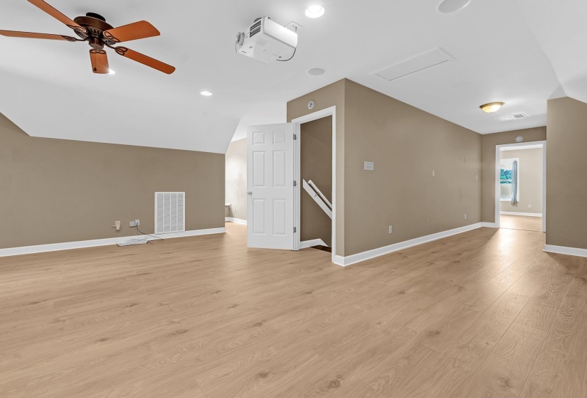 Spacious room featuring wood-finish flooring, neutral-toned walls, and a ceiling fan