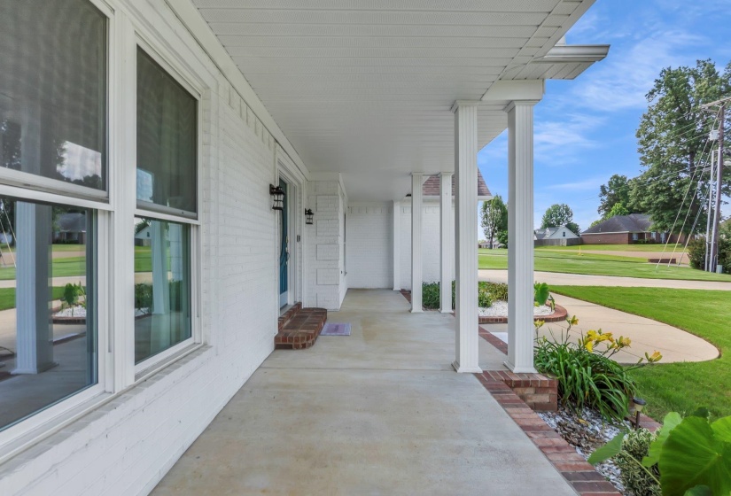 Covered front porch featuring white brick exterior, white columns, and concrete flooring