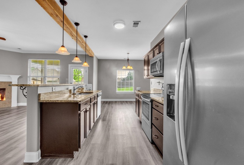 Kitchen featuring granite countertops, dark wood-finish cabinetry, stainless steel appliances, and wood-finish flooring