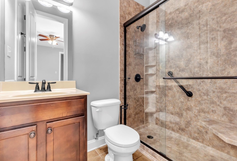 Bathroom featuring a glass-enclosed shower with a built-in bench and recessed shelving. Attached to second bedroom.