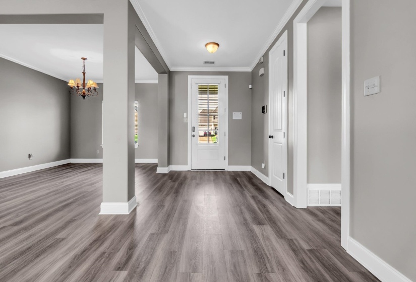 Foyer featuring wood-finish flooring, light gray walls, a white paneled front door with integrated blinds, and white trim throughout