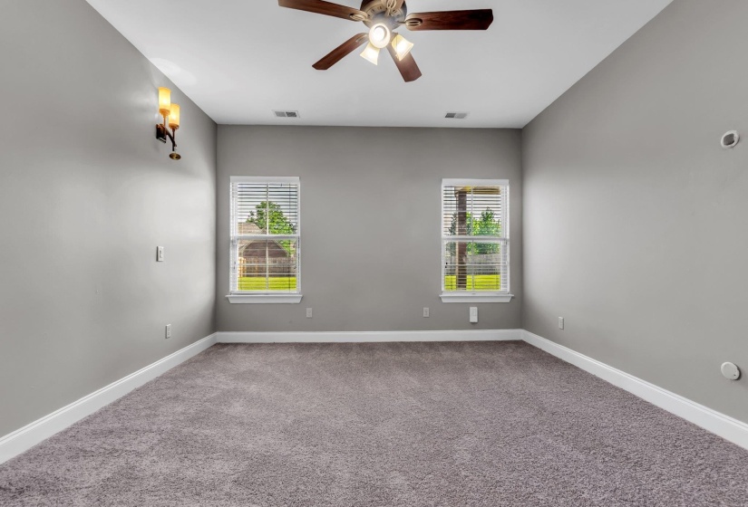 Spacious room featuring gray carpet flooring, white baseboards, and light gray wall paint