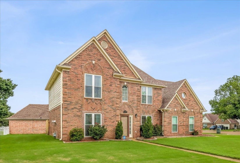 Traditional two-story brick residence with a gabled roofline and attached garage