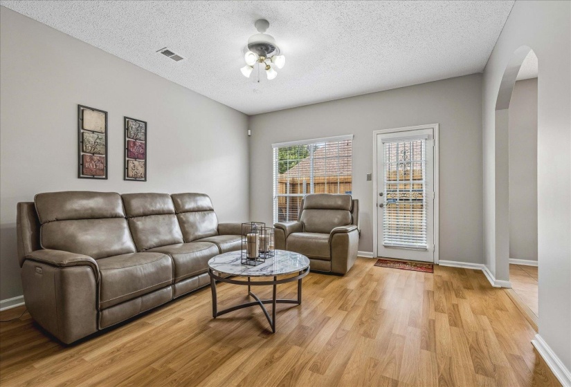 Living area featuring wood-finish flooring, light gray wall paint, and a ceiling fan with integrated lighting