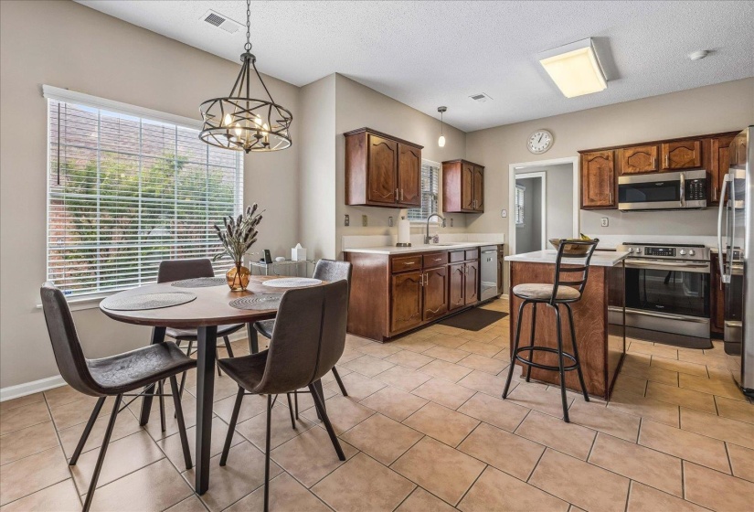 Kitchen and dining area featuring warm wood cabinetry, light countertops, and a tiled floor