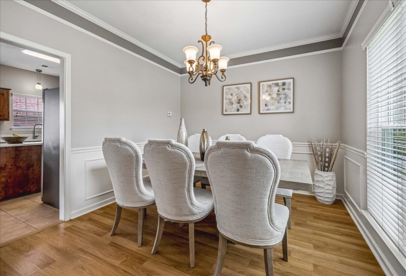 Formal dining space featuring wood-finish flooring, wainscoting, and crown molding