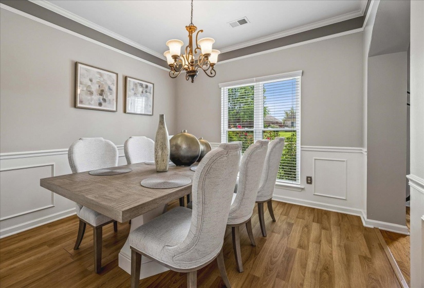 Formal dining space featuring wood-finish flooring, wainscoting, and a decorative chandelier