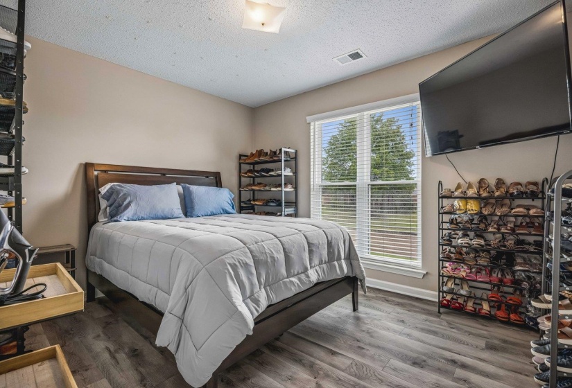 Bedroom featuring wood-finish flooring, a contemporary window with blinds, and neutral painted walls