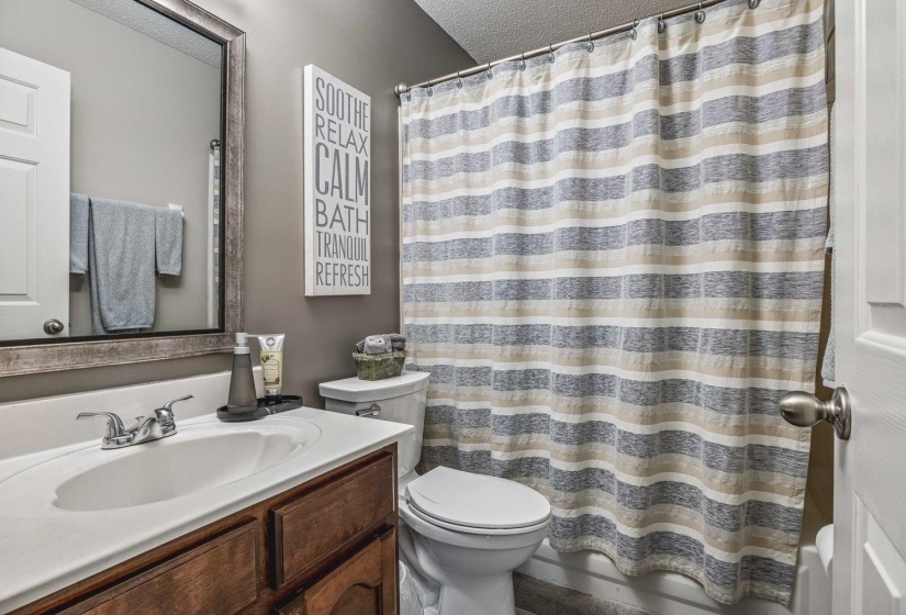 Vanity with a wood-finish cabinet, integrated white sink, and chrome faucet