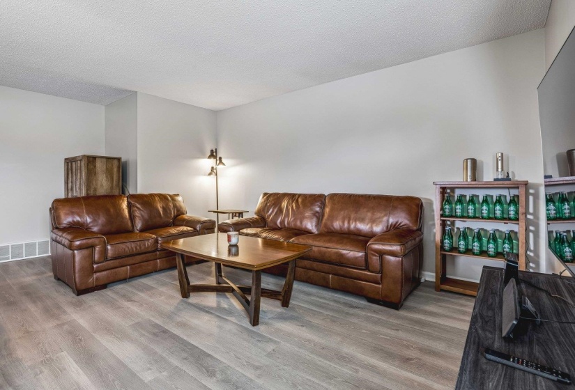 Spacious living area featuring wood-finish flooring, light-toned walls, and white trim