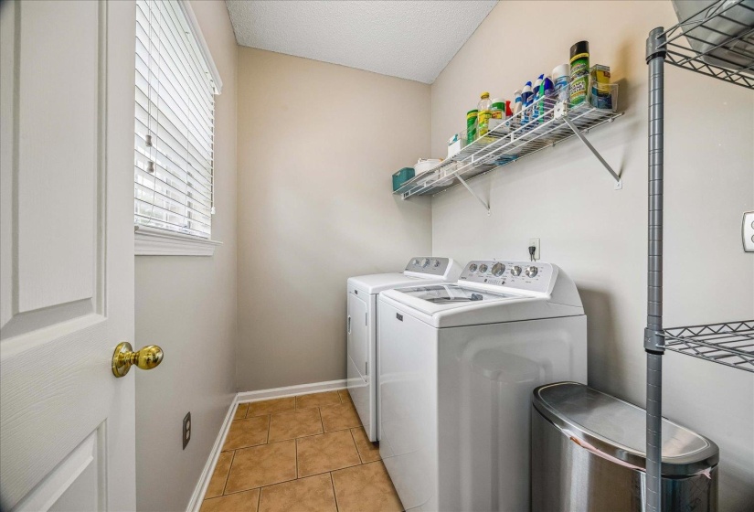 Laundry area featuring a window with blinds, tile flooring, and wall-mounted shelving