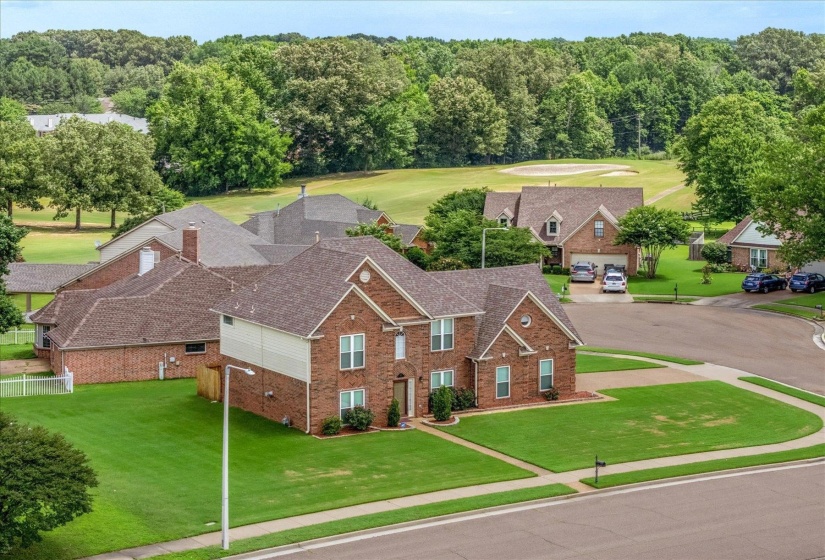 Brick exterior residence with a gabled roofline, featuring a two-story design, a well-maintained lawn, and a paved driveway leading to an integrated garage