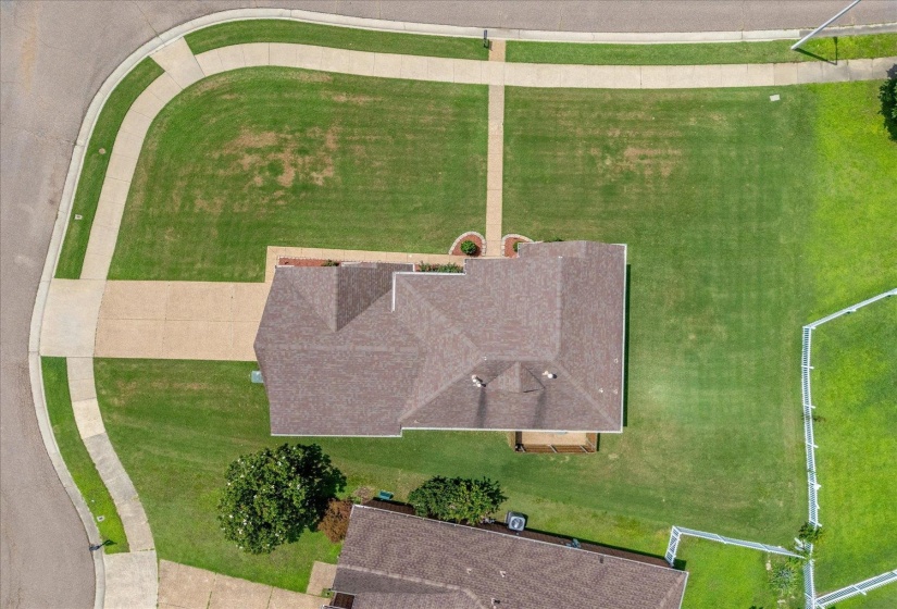 Aerial property overview showcasing a brown shingle roof, concrete driveway, and established walkways
