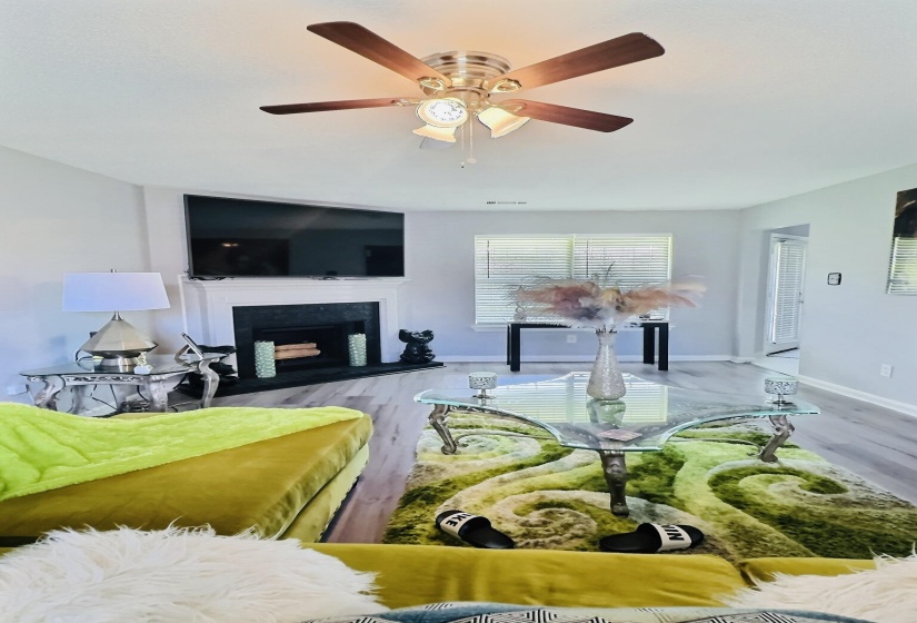 Bright living space featuring wood-finish flooring and a central ceiling fan with integrated lighting