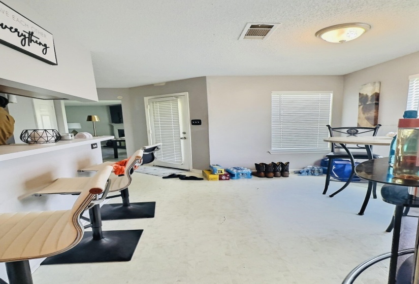 Kitchen area with light-toned flooring, featuring a breakfast bar with built-in cabinetry