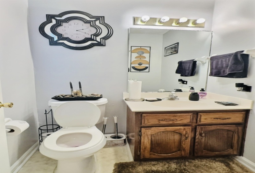 Bathroom featuring a wood-finish vanity with a laminate countertop, integrated sink, and a large wall-mounted mirror