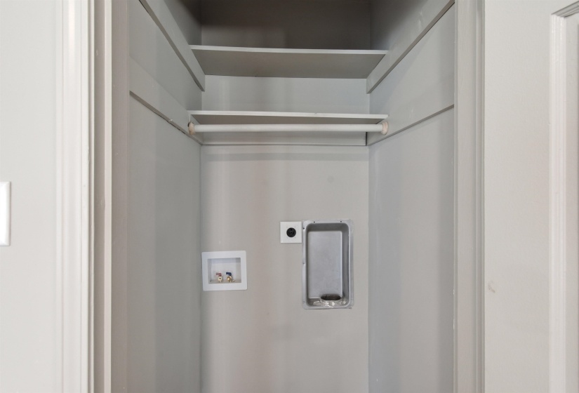 Laundry closet featuring utility hookups, upper shelving, and a clothing rod