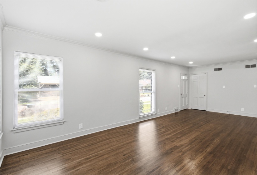 Spacious interior room featuring rich wood-finish flooring, recessed lighting, and crown molding