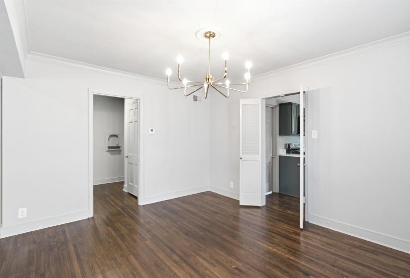 Open-concept room featuring wood-finish flooring, a contemporary chandelier, white painted walls, and crown molding