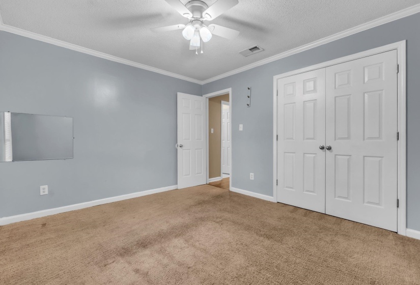 Interior room featuring light blue walls, a ceiling fan with light kit, and crown molding