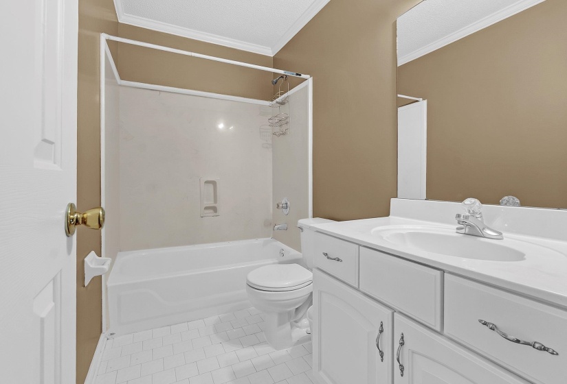 Full bathroom with a white vanity featuring a single basin sink, white cabinetry with decorative hardware, and a framed mirror