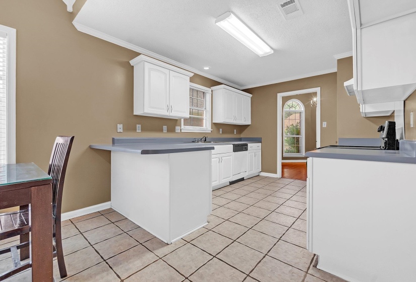 Kitchen featuring white cabinetry with silver hardware, gray countertops, a dishwasher, and tile flooring