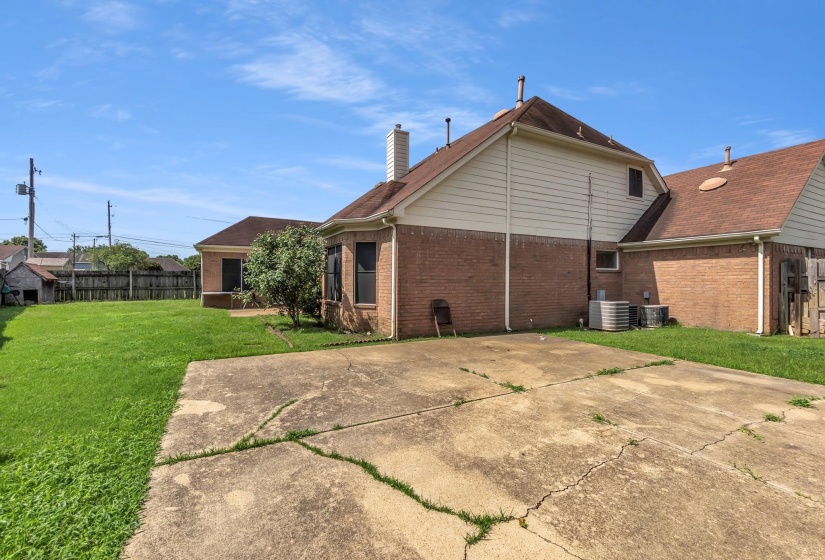Side exterior featuring brick and siding finishes, concrete driveway, and a spacious lawn area