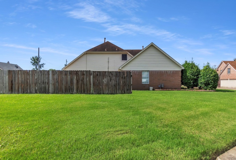 Expansive grassy lawn bordered by a wood privacy fence